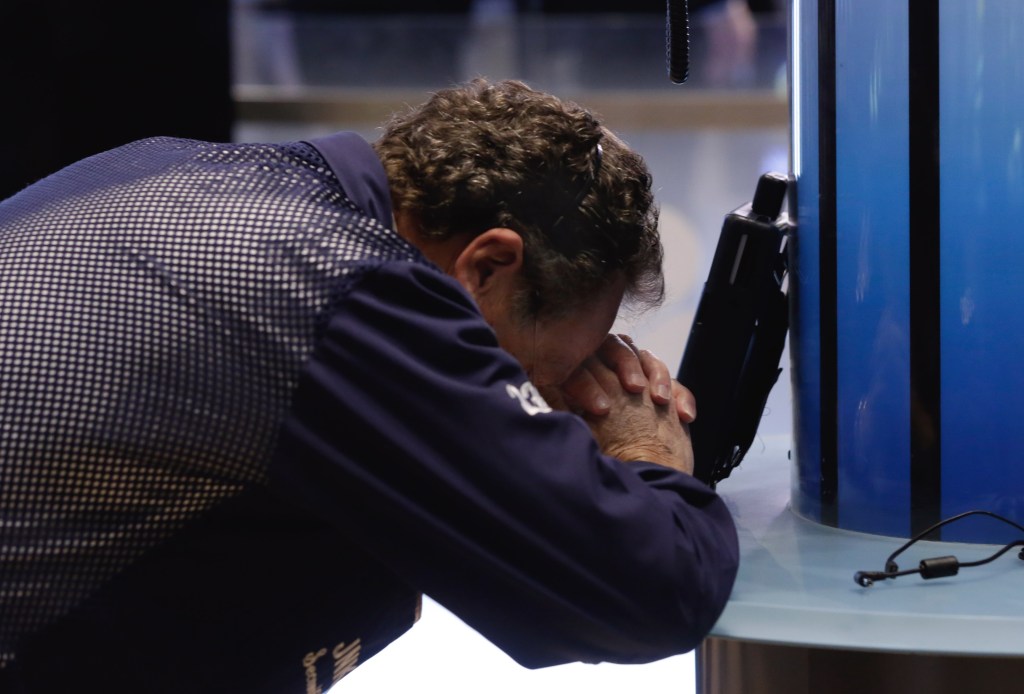 A Wall Street trader rests his head in his hands 