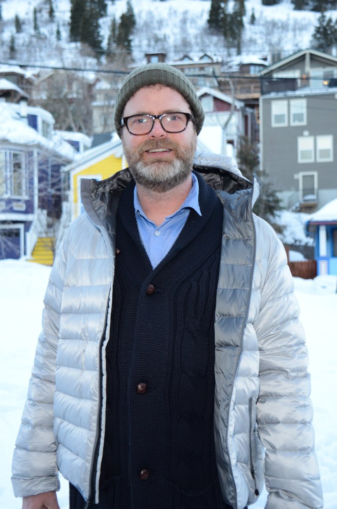 Photo of Rainn Wilson in a silver coat. 