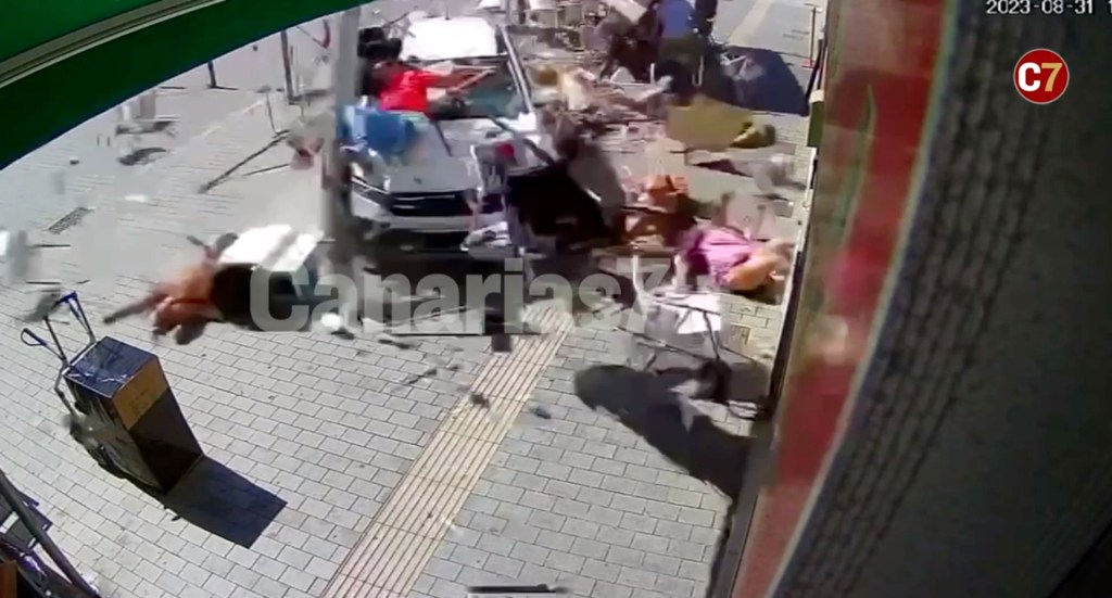 A woman in a pink dress could be seen on the ground, surrounded by debris as the man remains on the hood of the vehicle.