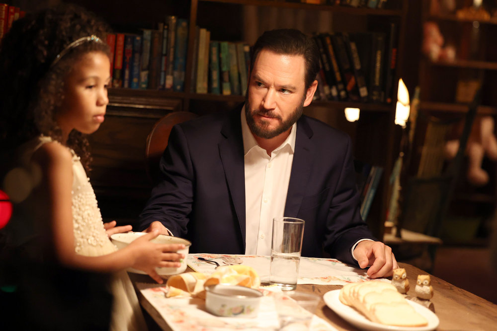 Mark-Paul Gosselaar sits at a table, looking at a little girl. 