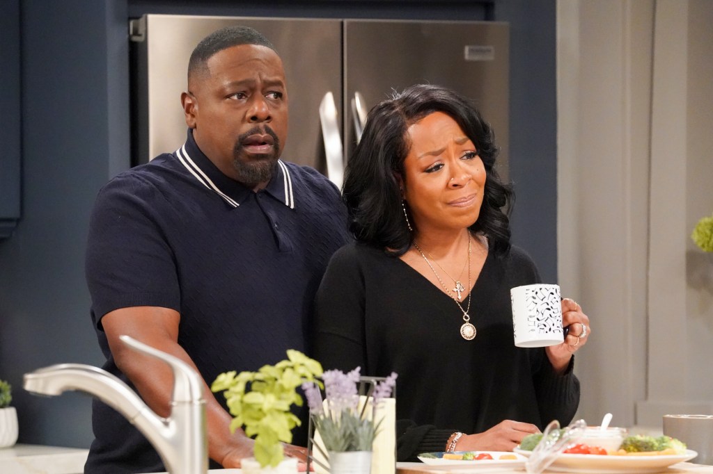Cedric the Entertainer and Tichina Campbell as Calvin and Tina in a scene from "The Neighborhood" on CBS. They're standing in a kitchen and Tina is holding a coffee mug.