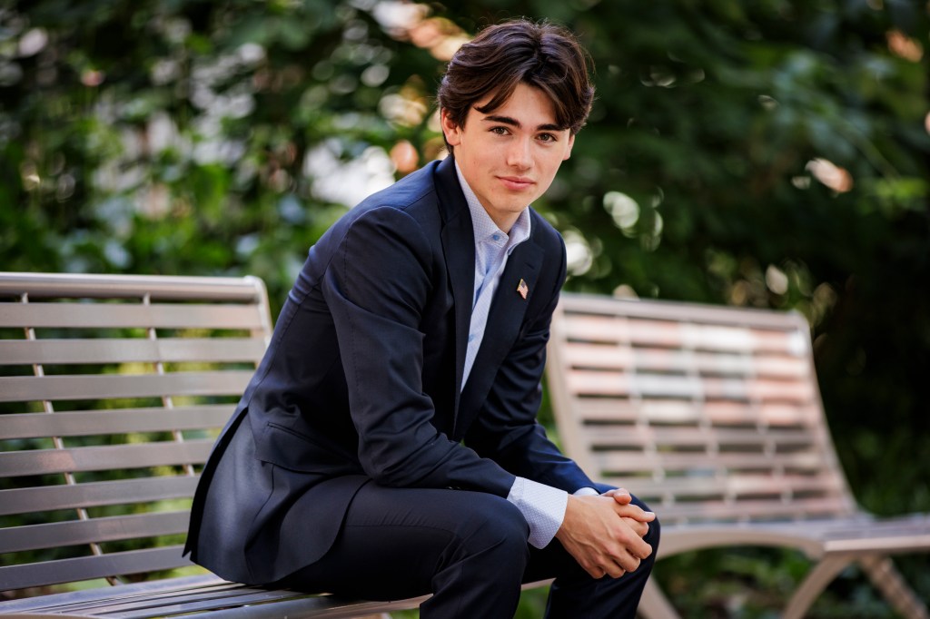 Kieran Laffey in suit, sitting on a bench outside. 