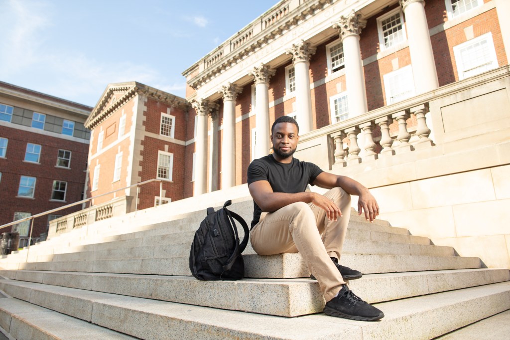 Daniel Isdrense sitting on steps outside on Syracuse University campus. 