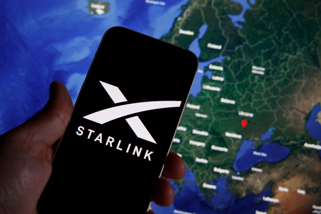An image of the Starlink logo on a smart phone with a map in the background.