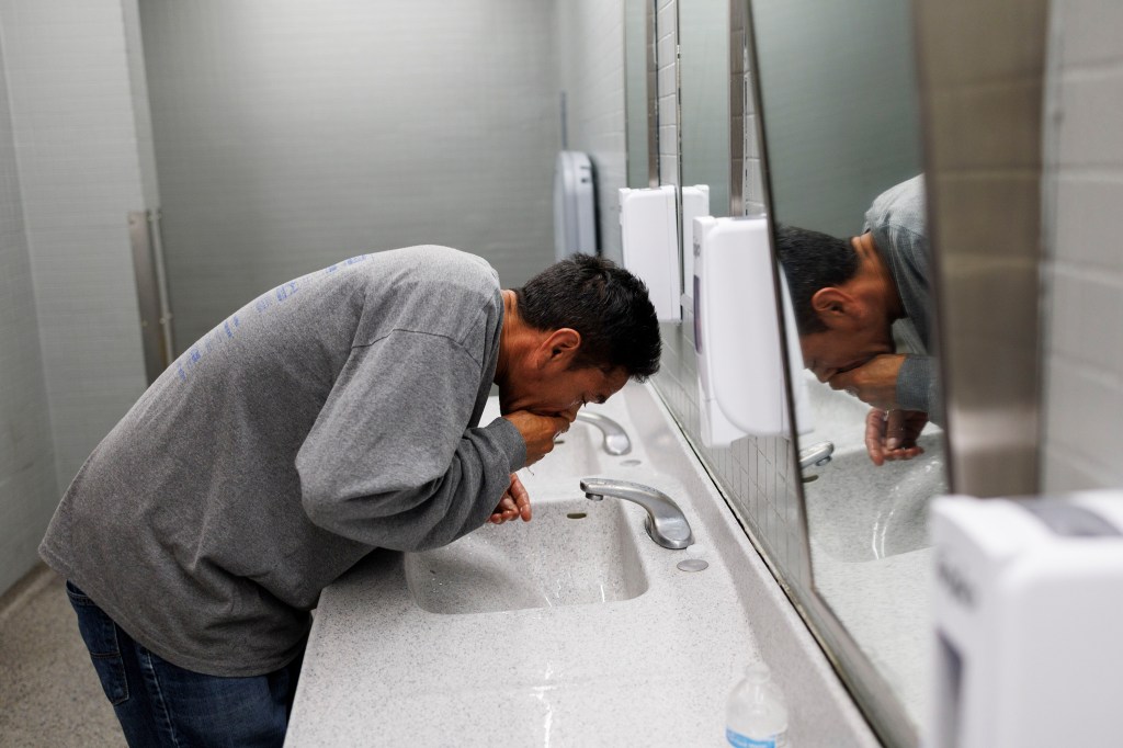 Jimmy Arias, a migrant from Venezuela washes his face in a bathroom in the O'Hare International Airport where the city of Chicago has set up a makeshift shelter.