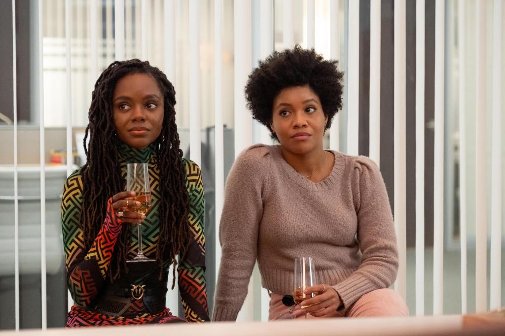 Hazel (Ashleigh Murray) sitting with Nella (Sinclair Daniel) in an office sipping wine. 