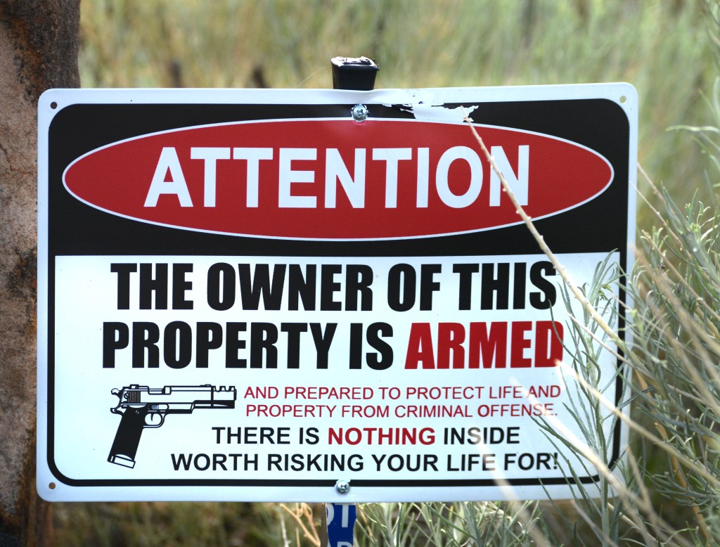 A photo of a sign saying the owner is armed.