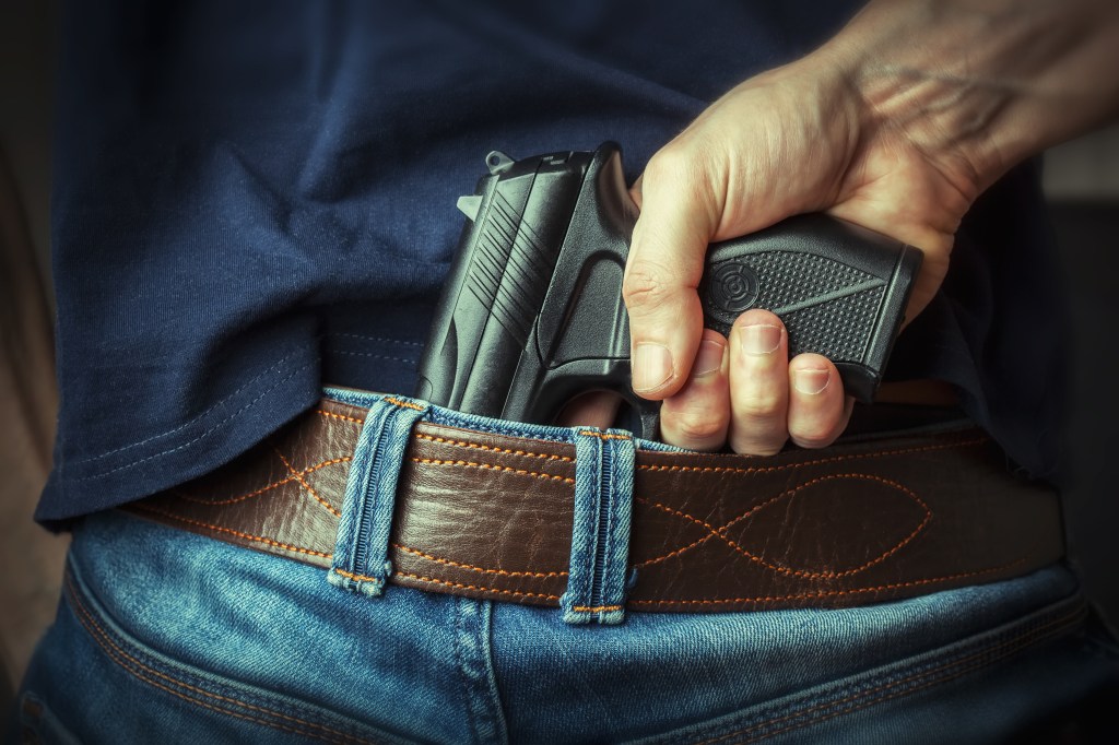 A photo of a man with a gun in his jeans.