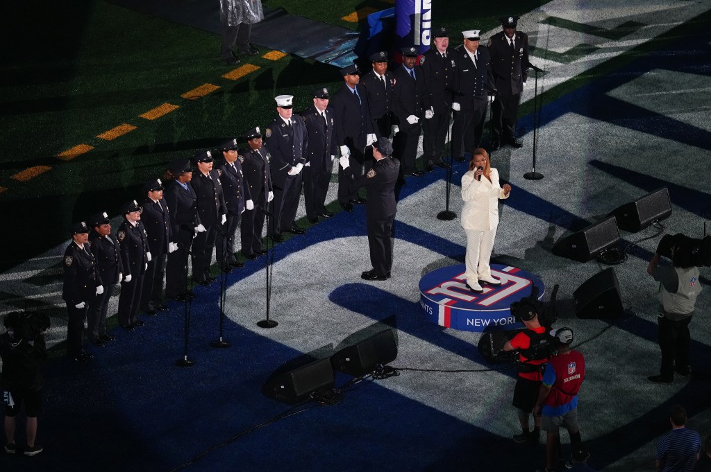 In a clip posted to X (formerly Twitter), the "Hollywood" actress, 53, can be seen taking the stage at MetLife Stadium in a crisp, white two-piece suit surrounded by members of the NYPD and FDNY choir. 