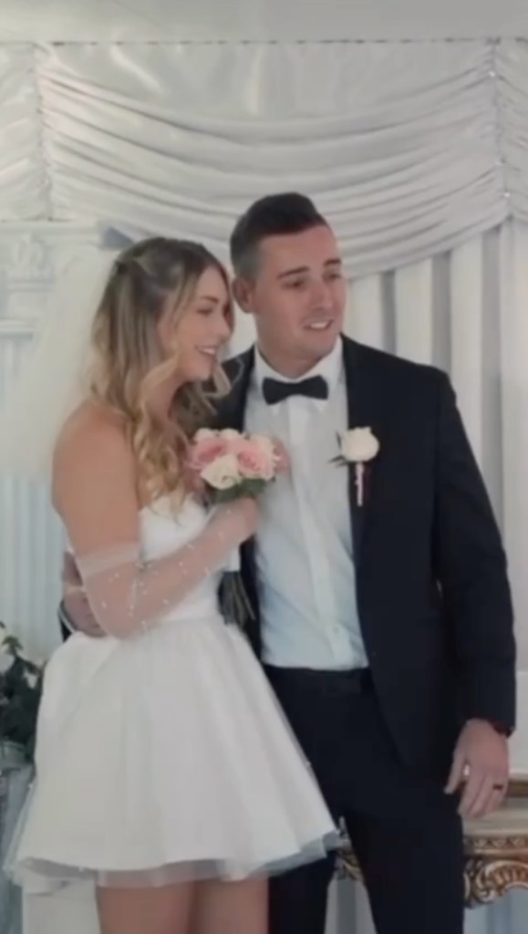 Groom stands with his arm around the bride's waist