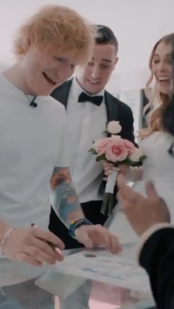 Ed Sheeran smiles as he signs a marriage certificate. 