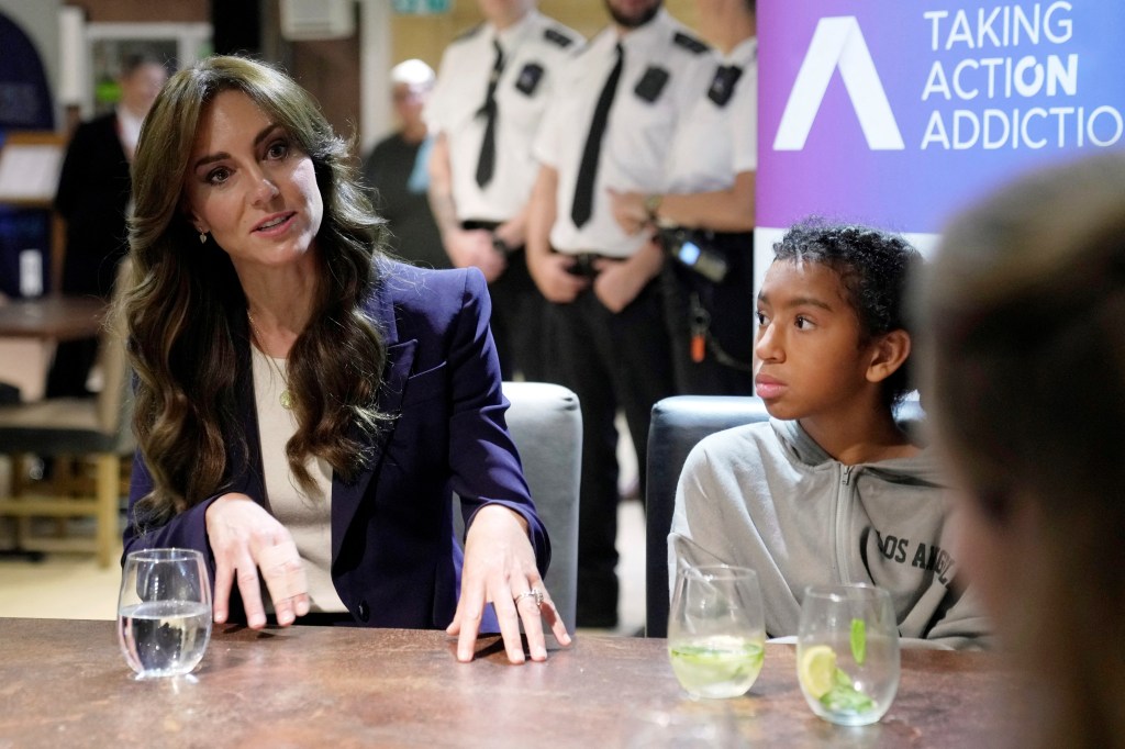 Kate Middleton sitting with a young boy talking. 