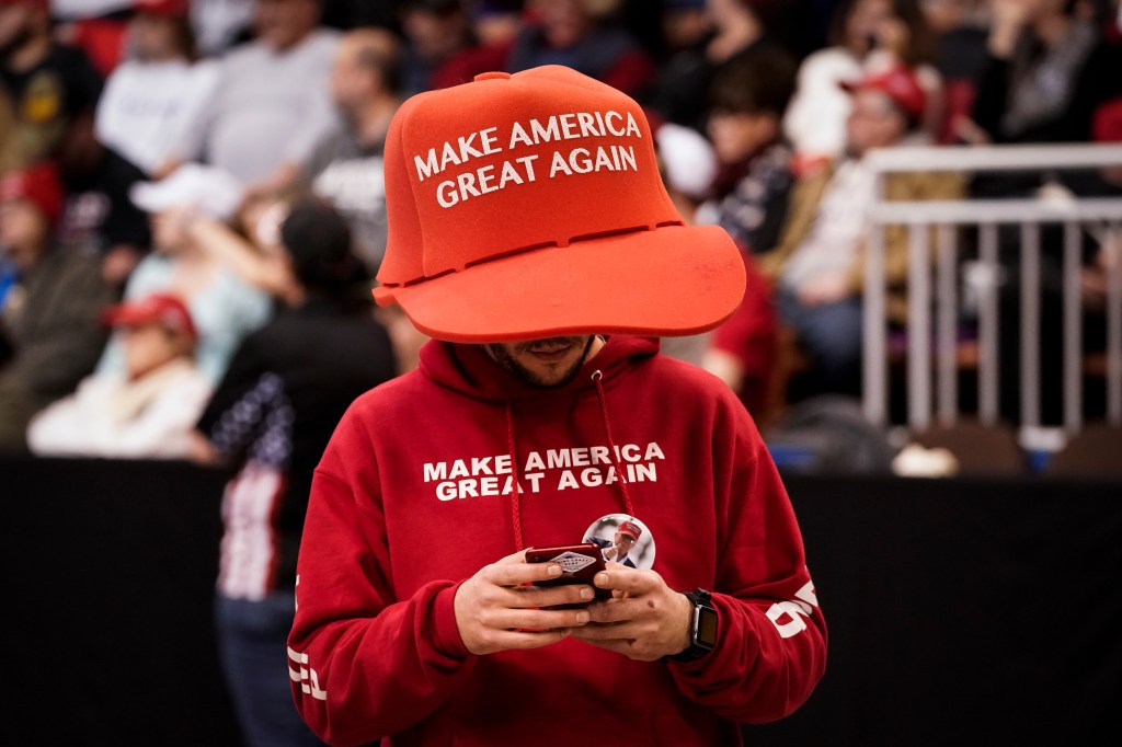 A supporter of U.S. President Donald Trump wears an oversize "Make America Great Again Hat" as he waits for the start of a "Keep America Great" rally at Southern New Hampshire University Arena on February 10, 2020 in Manchester, NH