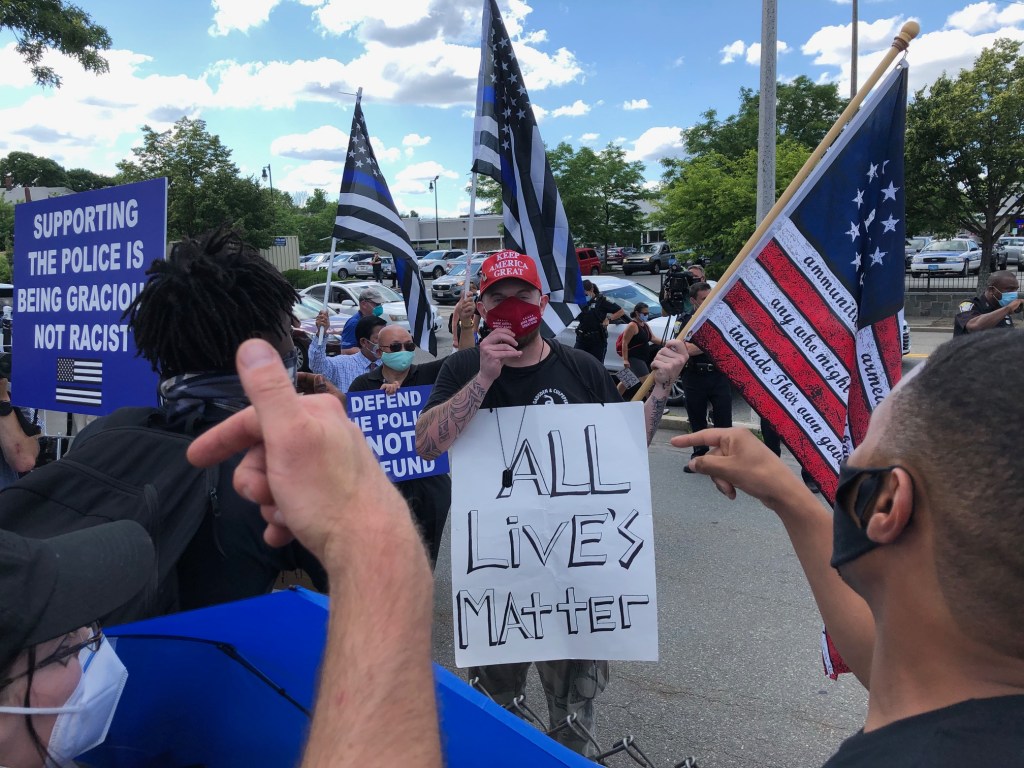 Protestors argue with a counter protester holding an "all lives matter" sign during a Black Lives Matter rally on Town Field in Boston's Dorchester on Juneteenth, June 19, 2020