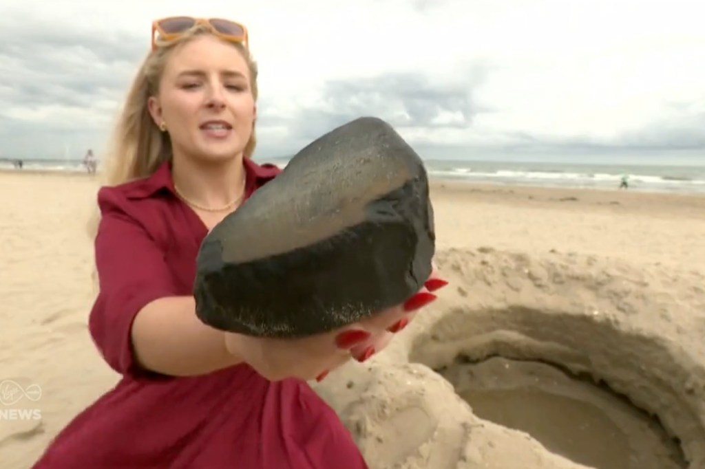 A Virgin Media News reporter holds the supposed meteor alongside the supposed crater where it supposedly landed