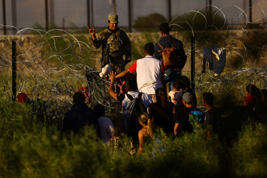 A member of the Texas National Guard stands guard with the purpose of inhibiting the crossing of migrants to the United States.