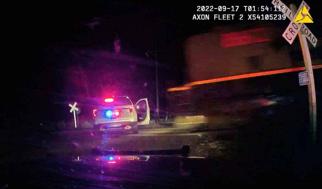 This screen grab from dash camera video provided by the Fort Lupton Police Department shows a freight train barreling toward a parked police car with a suspect inside, Sept. 16, 2022, in Fort Lupton, Colo