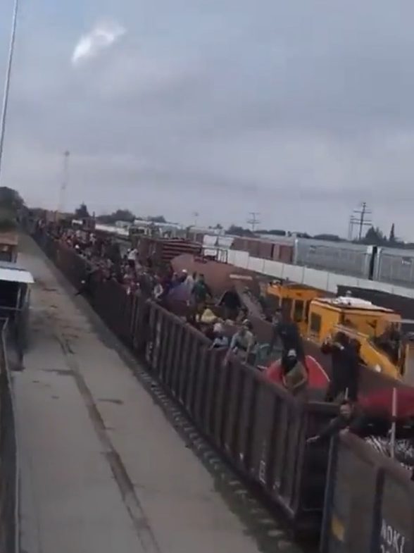 A screengrab from the footage shows the cargo train filled to the brim with migrants.