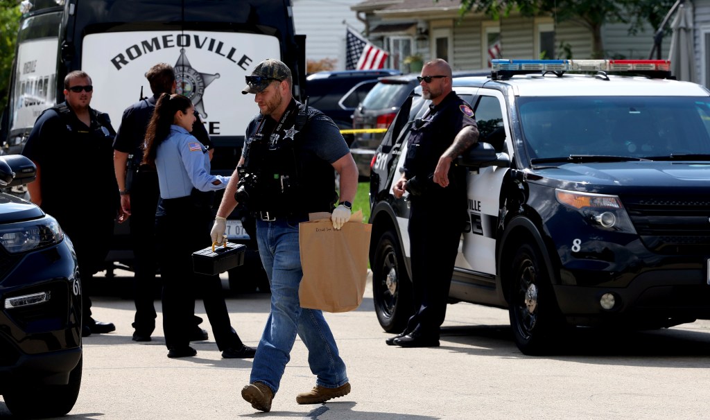 A Romeoville Police officer carries out a brown bagged marked with the words, "Drywall from hallway" from inside of the home where four people were shot to death on Monday, Sept. 18, 2023, in Romeoville.