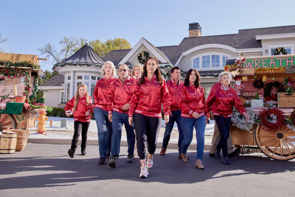 Charlotte Kay Witt, Carrie Morgan, Peter Jacobson, Melissa Peterman, Lacey Chabert, Wes Brown, Laura Wardle, Ellen Travolta in "Haul Out the Holly: Lit Up" wearing red jackets. 
