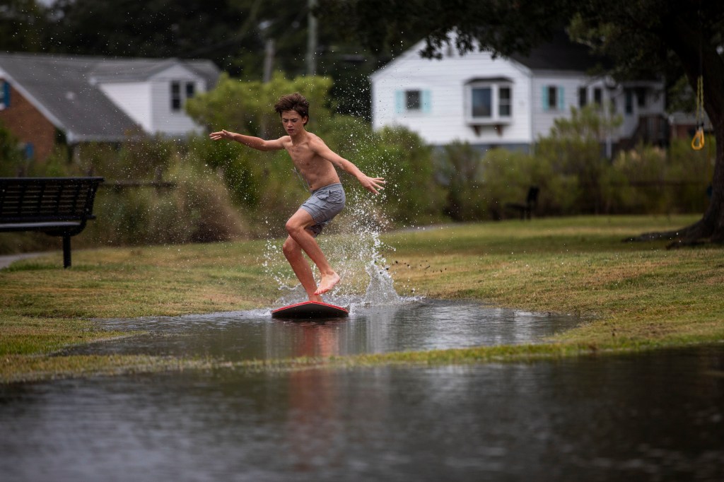 A Virginia boy skimboards in floodwaters as Tropical Storm Ophelia approached the area on Sept. 22, 2023.