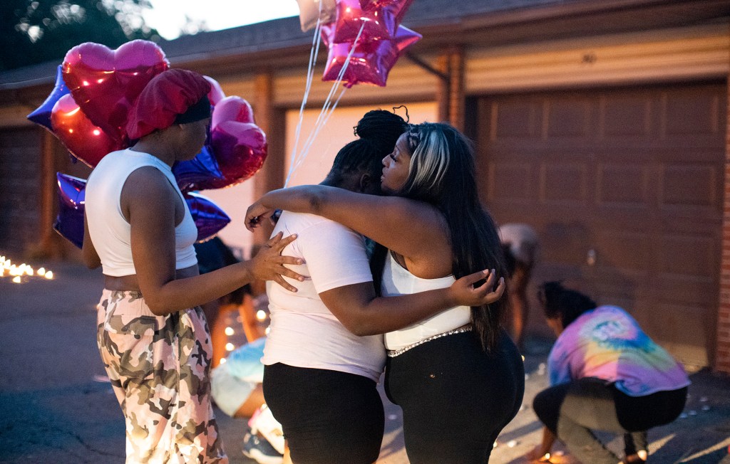 Friends comfort each other at a private candlelight vigil in Columbus, Ohio, held for 21-year-old Ta'Kiya Young.