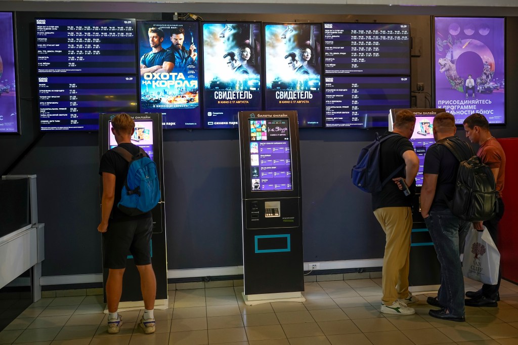 People stand at ticket machines in a cinema lobby inside a shopping mall in Moscow, Russia, Thursday, Aug. 17, 2023.