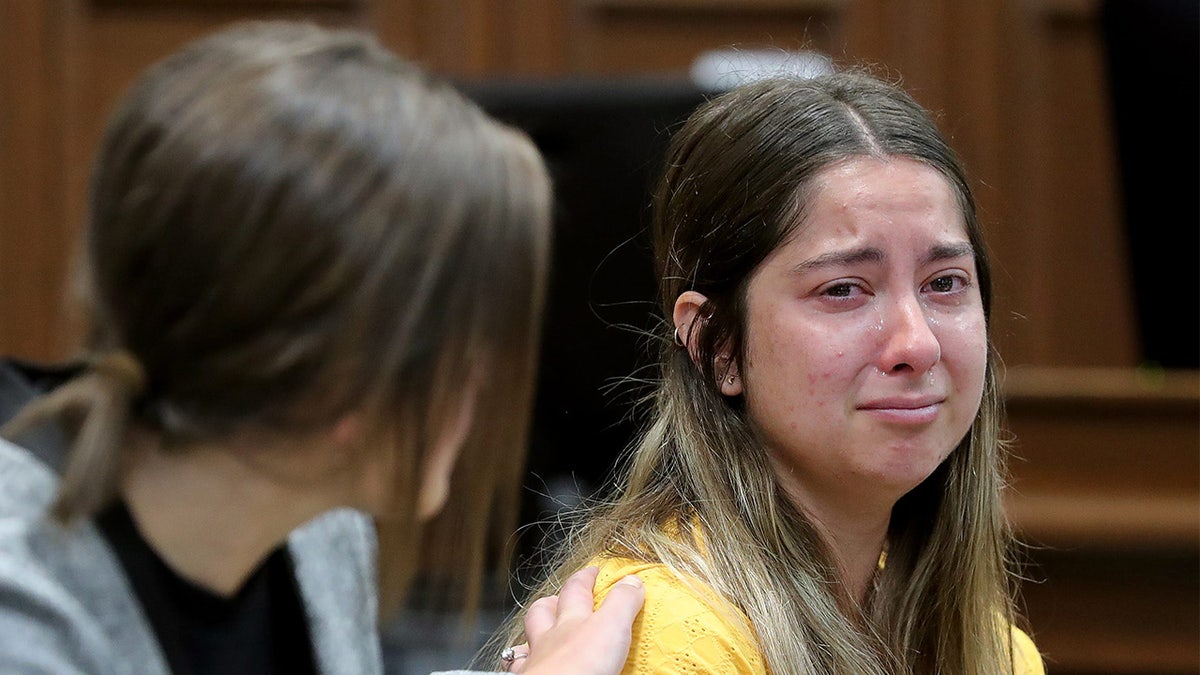 Woman in yellow shirt sobs.