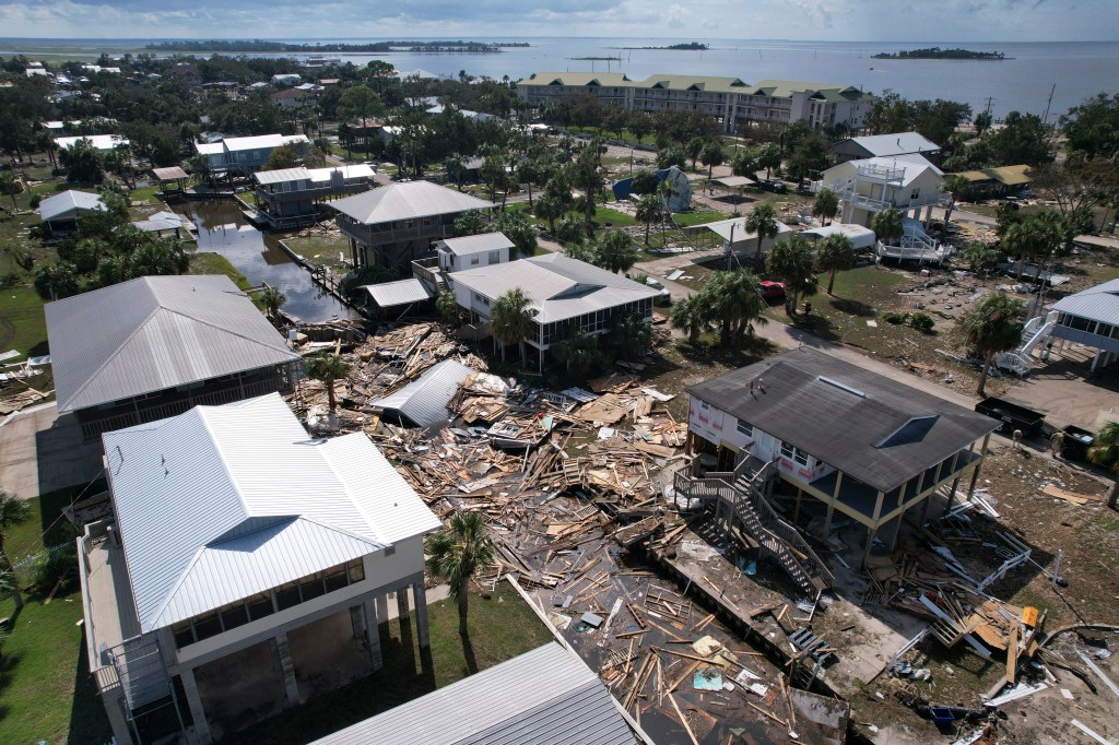 Debris from homes swept off their lots chokes a canal amid homes on stilts which remain standing, in Horseshoe Beach, Fla., on Aug. 31, 2023. 