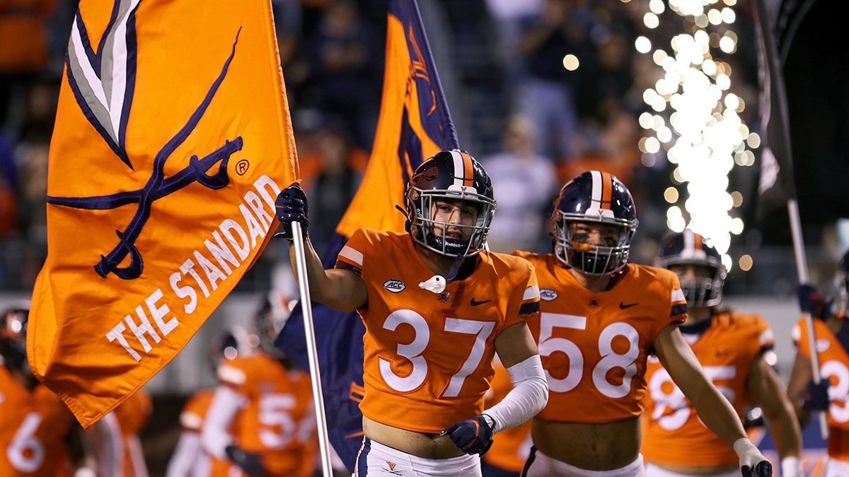 Virginia football players carry their flag