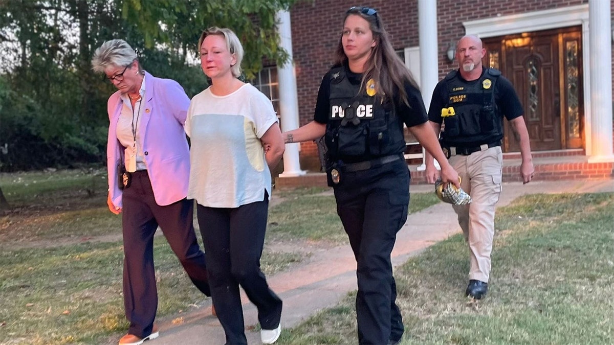 Alissa McCommon in handcuffs is escorted to a police vehicle