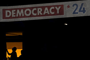 A digital board reads "Democracy 24."