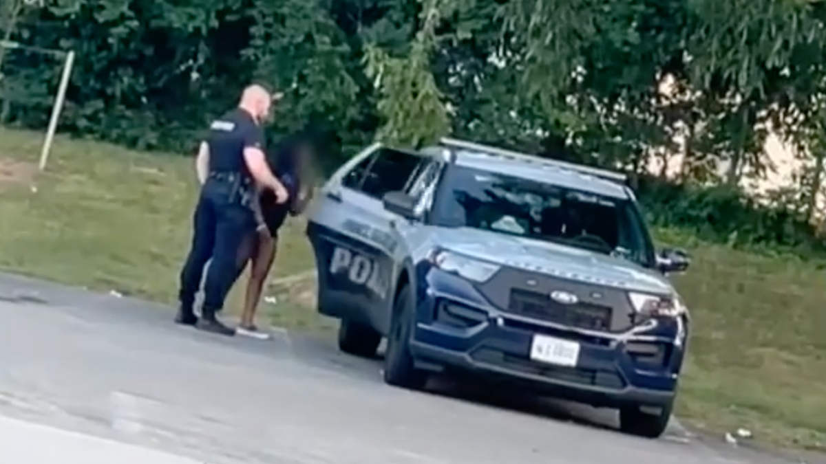 still shot of police officer with woman entering back of cruiser