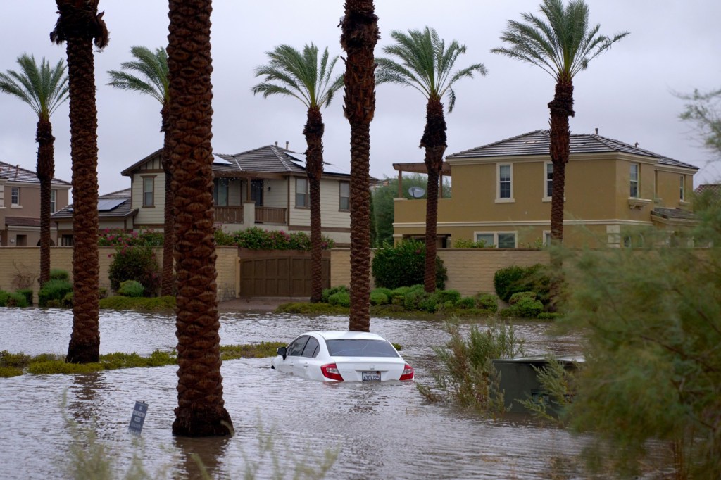 A car is submerged in flooded water as Tropical Storm Hilary arrives in Cathedral City, Calif. 