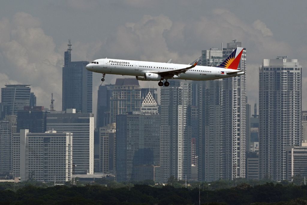 A Philippine Airlines Airbus A321 passenger aircraft prepares to land at the Ninoy Aquino International Airport as the skyline of the Makati business centre is seen from Taguig City, suburban Manila on August 19, 2023. 