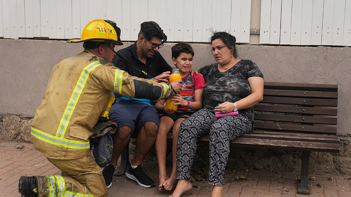 Israeli firefighter hands water to family