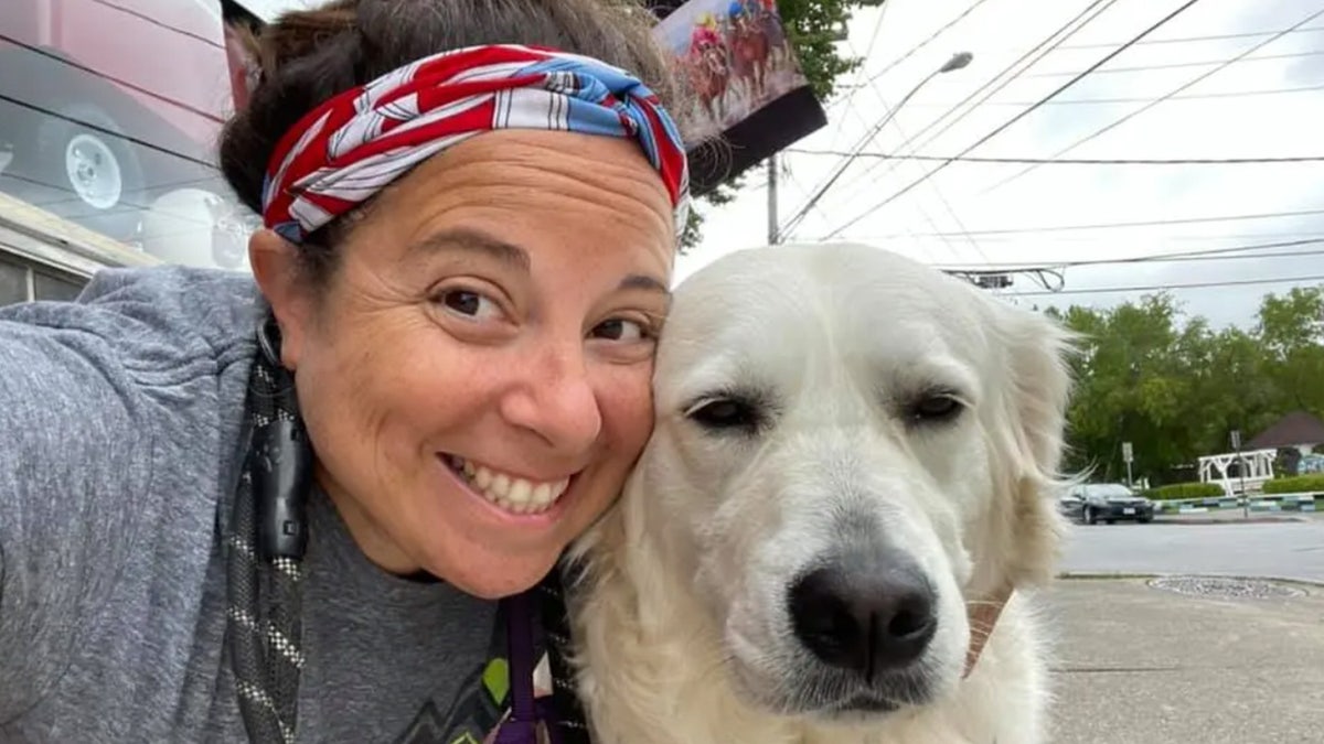 Woman poses with golden retriever.