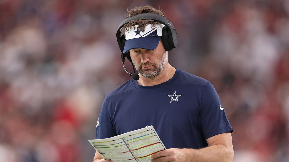 Brian Schottenheimer looks at a play sheet during a Cowboys game