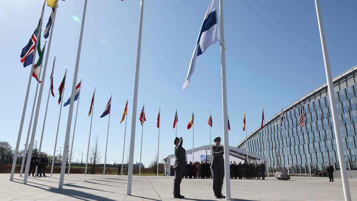 Military personnel raise the flag of Finland