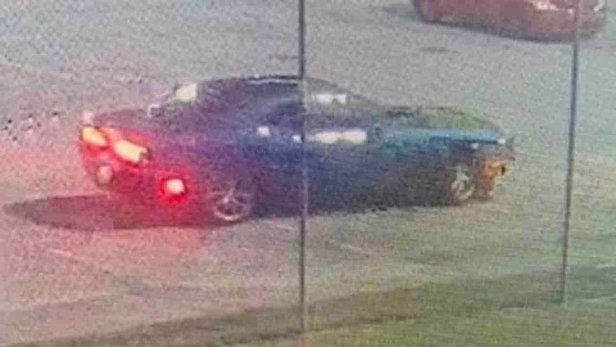 blue Dodge Challenger outside jail fence