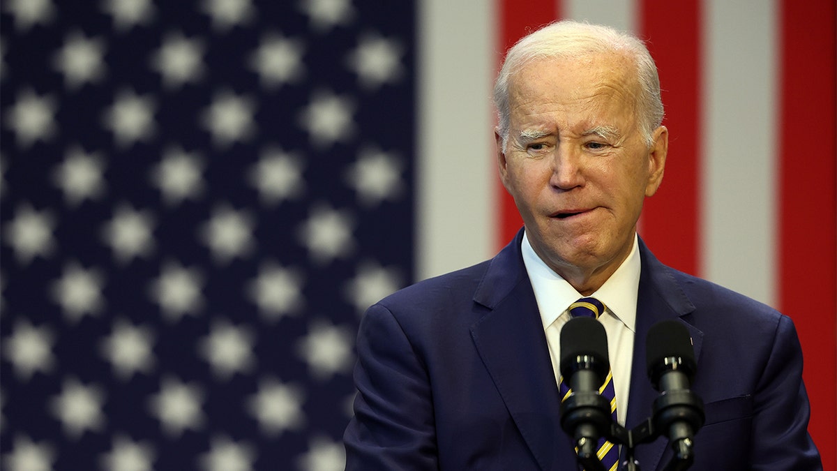 Joe Biden at microphone, US flag behind him