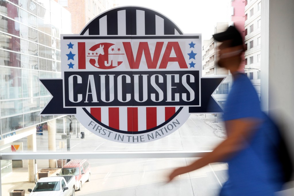 A pedestrian walks past a sign for the Iowa Caucuses on a downtown skywalk, in Des Moines, Iowa, on Feb. 4, 2020.