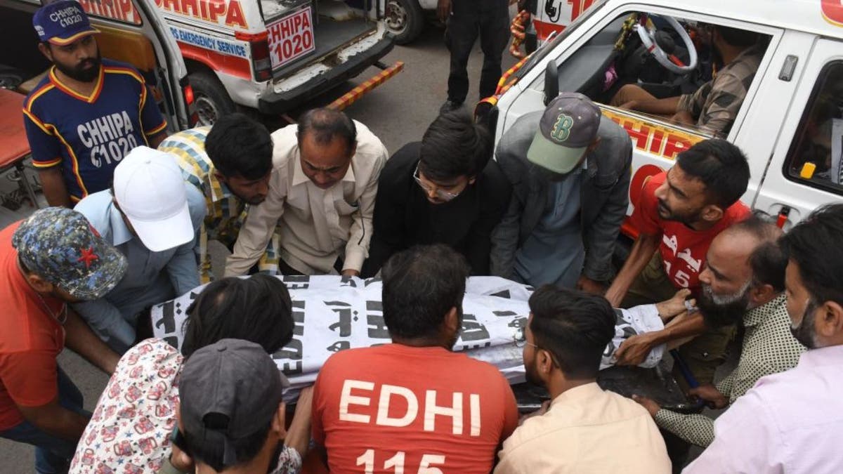 Rescuers place a body in a body bag into an ambulance in Pakistan