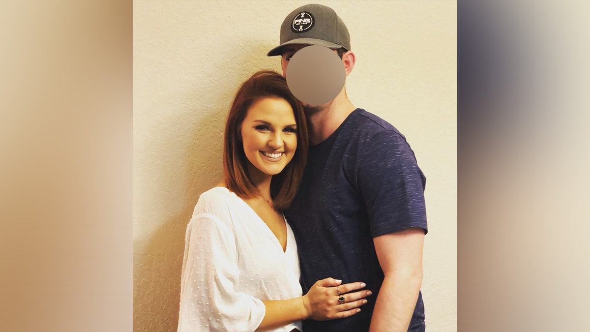 Woman and man wth baseball hat embrace in photo.