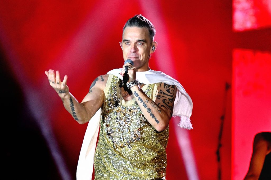 A woman, said to be in her 70s, is hospitalized in a coma after falling down six rows of seats at Robbie Williams' concert Thursday.
