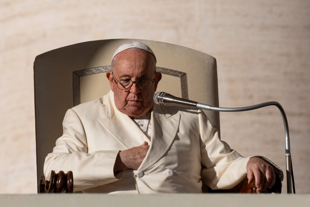 Pope Francis seated in front of a microphone