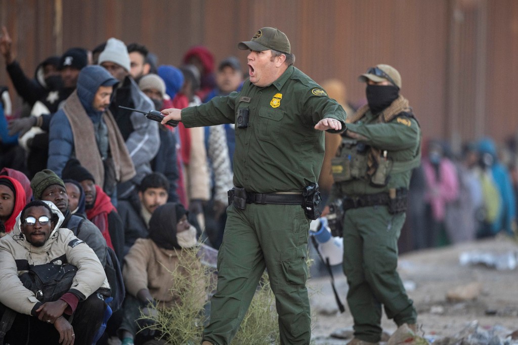 A U.S. Border Patrol agent shouts at immigrants