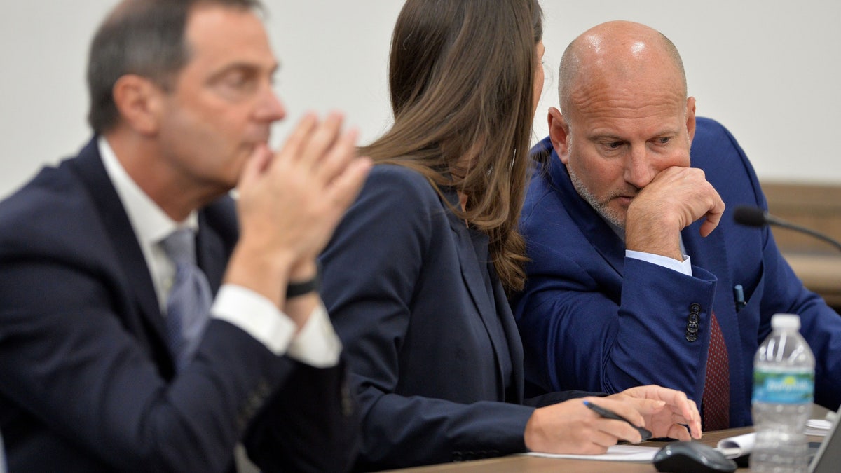 Attorney Steven Bertolino, right, speaks with attorney Laura Kelly, center, in court