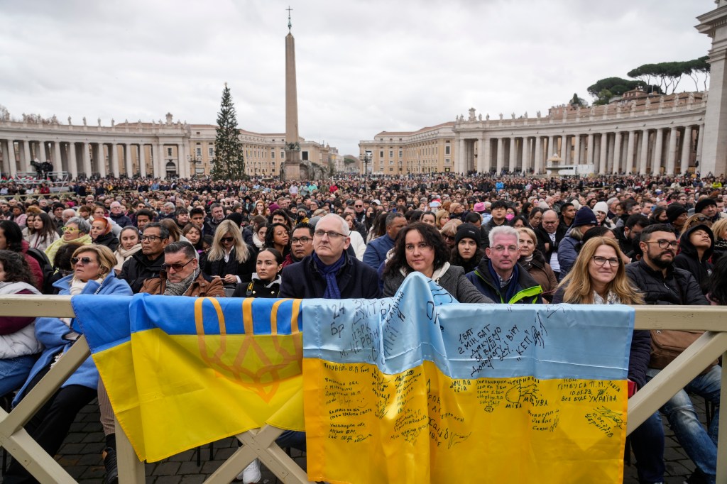 People stand by Ukrainian flags as they listen to Pope Francis delivering the Urbi et Orbi (Latin for 'to the city and to the world' ) Christmas' day blessing from the main balcony of St. Peter's Basilica at the Vatican, Monday Dec. 25, 2023.