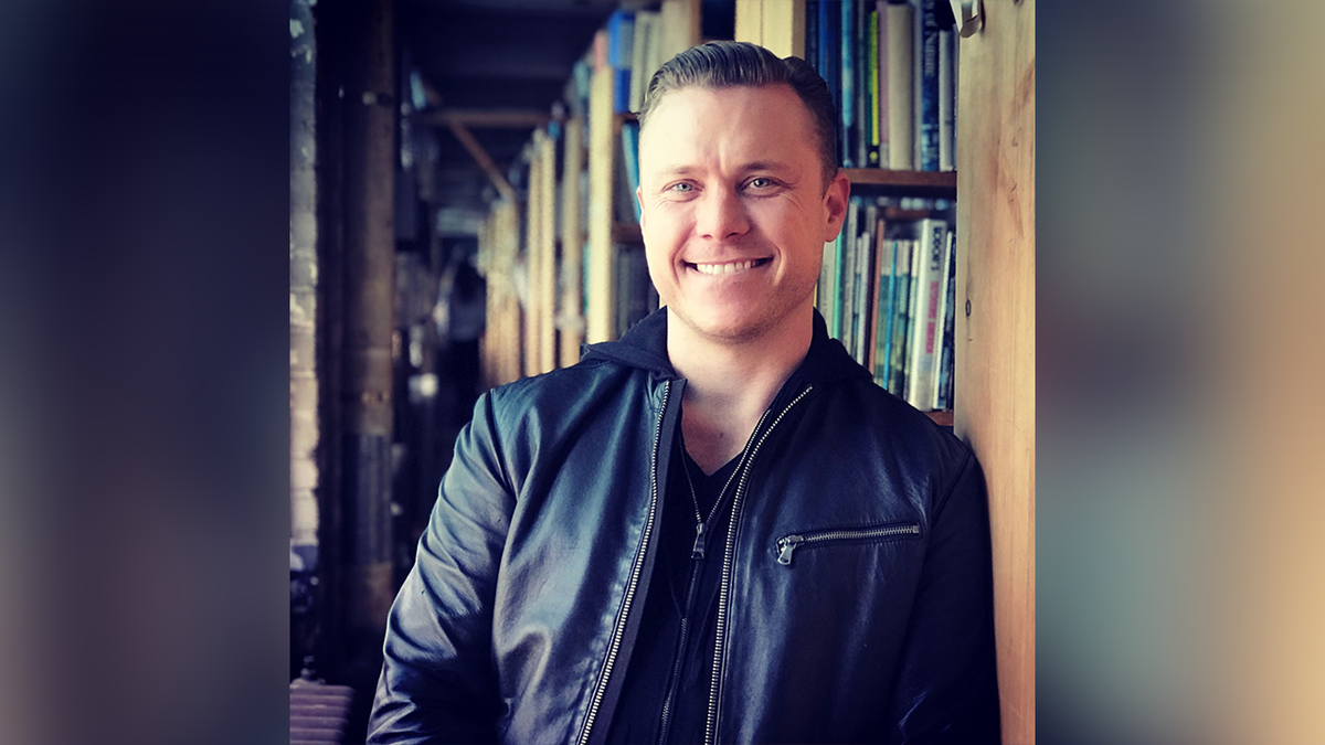 Bob Lee leaning against bookshelf